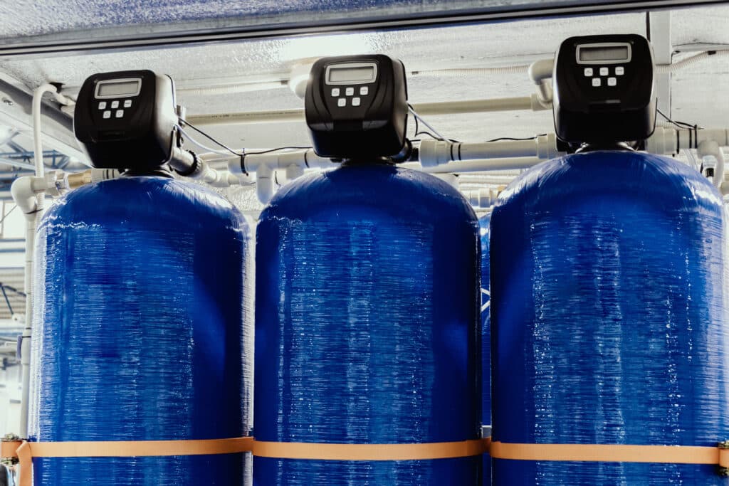 Three blue commercial water softeners standing in a row